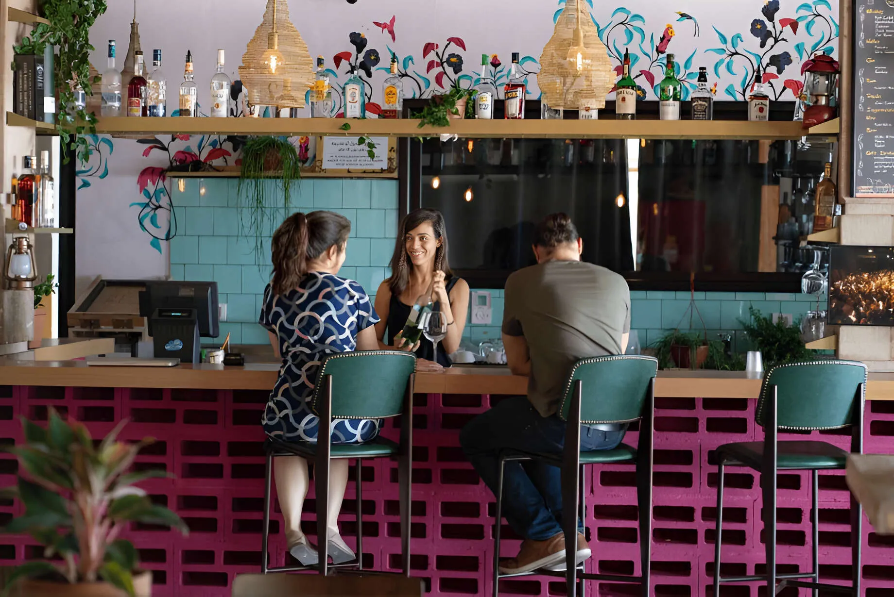 Father and daughter sitting on stools in a colourful room across from a lady